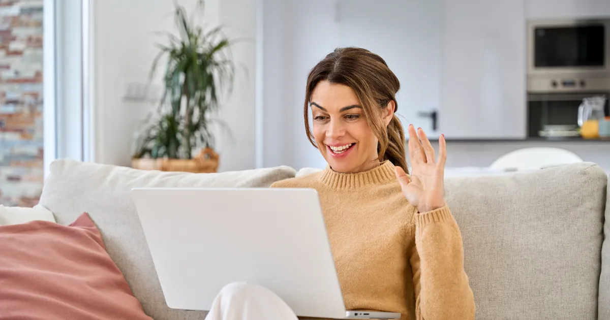 A smiling woman on a video call at her laptop at home